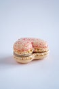 A single vanilla flavoured heart-shaped French macaron, copy space on neutral background