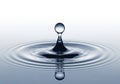 A single water droplet rises from a calm liquid surface, creating a Royalty Free Stock Photo