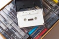 Single white audio cassette on top of the box with many tapes