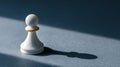 Single white chess pawn casting a shadow on textured surface with dramatic lighting and dark background Royalty Free Stock Photo