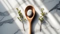 A single white egg rests in a wooden spoon on a marble surface with delicate green sprigs and dappled light Royalty Free Stock Photo