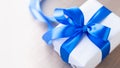 Single white gift box with blue ribbon on wood table close up Royalty Free Stock Photo