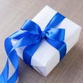 Single white gift box with blue ribbon on wood table close up Royalty Free Stock Photo