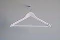 A single white hanger hangs straight on a plain gray wall, providing a simple and clean background Royalty Free Stock Photo