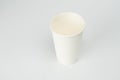 A single white paper cup sits on a flat surface, empty with the rim visible Soft, even lighting suggests an indoor setting The Royalty Free Stock Photo