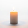 A single white pillar candle is burning against a plain background Royalty Free Stock Photo