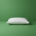 A single white pillow rests on a smooth, green surface, with a matching green Royalty Free Stock Photo