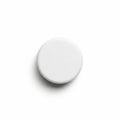 A single white round tablet is centered on a plain white background Royalty Free Stock Photo