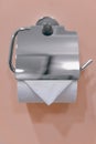 Single white toilet paper roll metallic dispenser mounted on the wall Royalty Free Stock Photo