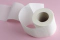 Single white toilet paper roll on pastel pink background. Space for text. Royalty Free Stock Photo