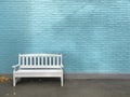 Single white wooden bench on a background of blue brick wall. The facade of the building painted in blue. Vintage photo with copy Royalty Free Stock Photo