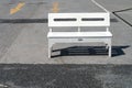 single white wooden bench is placed in afternoon sunlight on concrete floor of empty parking lot Royalty Free Stock Photo