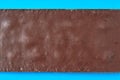 Single whole dark porous chocolate bar lies on blue table on kitchen. Top view