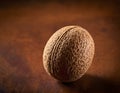 Single Whole Nutmeg Seed with Attached Mace Aril on Rustic Wooden Surface Royalty Free Stock Photo