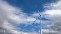 Single wind turbine against a heavily cloudy blue sky.