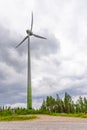 Single Wind Turbine in the middle of the green forest under blue sky with clouds. Windfarm, wind power plant Royalty Free Stock Photo