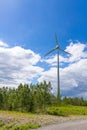 Single Wind Turbine in the middle of the green forest under blue sky with clouds. Windfarm, wind power plant Royalty Free Stock Photo