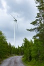 Single Wind Turbine in the middle of the green forest under blue sky with clouds. Windfarm, wind power plant Royalty Free Stock Photo