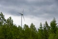 Single Wind Turbine in the middle of the green forest under blue sky with clouds. Windfarm, wind power plant Royalty Free Stock Photo