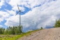 Single Wind Turbine in the middle of the green forest under gray clouds with sun. Windfarm, wind power plant Royalty Free Stock Photo