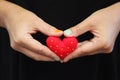 A single woman with her hands together holding a red felted heart