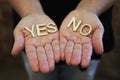 A single woman with her hands together with wooden letters forming the words Yes and No Royalty Free Stock Photo