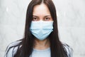 Single quarantined woman in medical mask calmly looks at the camera