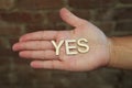 A single woman opening her hand with wooden letters forming the word Yes Royalty Free Stock Photo