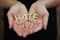 A single woman opening her hands with wooden letters forming the word Hate