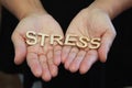 A single woman opening her hands with wooden letters forming the word Stress