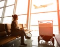 Single woman sitting in airport terminal and passanger plane fly