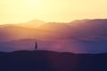 Single woman walking on the hill during sunset.