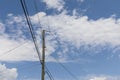 Single wood power pole with transmission wires radiating out in three directions against a blue sky with clouds, creative copy spa