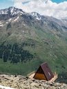 Single wooden house with a red roof on a hill high in the mountains with a beautiful view of the green valley on a Sunny day Royalty Free Stock Photo