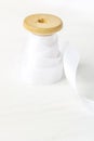 Single Wooden Spool Roll with Curly Silk Ribbon on White Wood Background. Sewing Crafts Hobby Concept