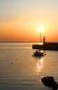 Mevagissey lighthouse against Pale sunrise with single yacht in harbour on a still morning in Cornwall