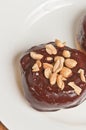 single yeast donut covered with chocolate frosting and salted peanuts