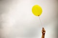 single yellow balloon under cloudy sky. hand holds the balloon rope up to the sky. Royalty Free Stock Photo