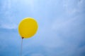 Single yellow balloon under cloudy sky. hand holds the balloon rope up to the sky. Royalty Free Stock Photo