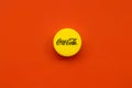 Single yellow bottle lid with Coca Cola logo on red background