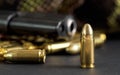 Single yellow brass bullet detail, black metal gun in background Royalty Free Stock Photo