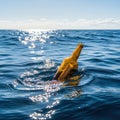 A lone yellow bottle cap bobs on the surface of the vast blue ocean under a bright sunny sky Royalty Free Stock Photo