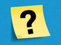 A single yellow post-it note with a large black question mark on a blue background isolated on white background Royalty Free Stock Photo