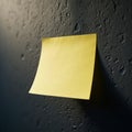 A single yellow sticky note is attached to a dark, textured wall Royalty Free Stock Photo