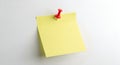 A single yellow sticky note pinned to a white surface with a red pushpin Royalty Free Stock Photo