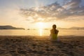 Single young woman sitting alone and looking through the sea on the beach Royalty Free Stock Photo