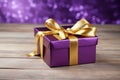 a singular gold gift box with a purple ribbon