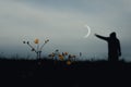 A sinister hooded figure standing in a field, out of focus. With a low camera angle. Reaching out to a crescent moon