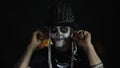 Sinister man with horrible Halloween skeleton makeup puts on headphones, starts dancing, celebrating
