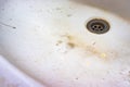 A sink drain hole with limescale or lime scale and rust on it, dirty rusty calcified bathroom washbowl with soap stains